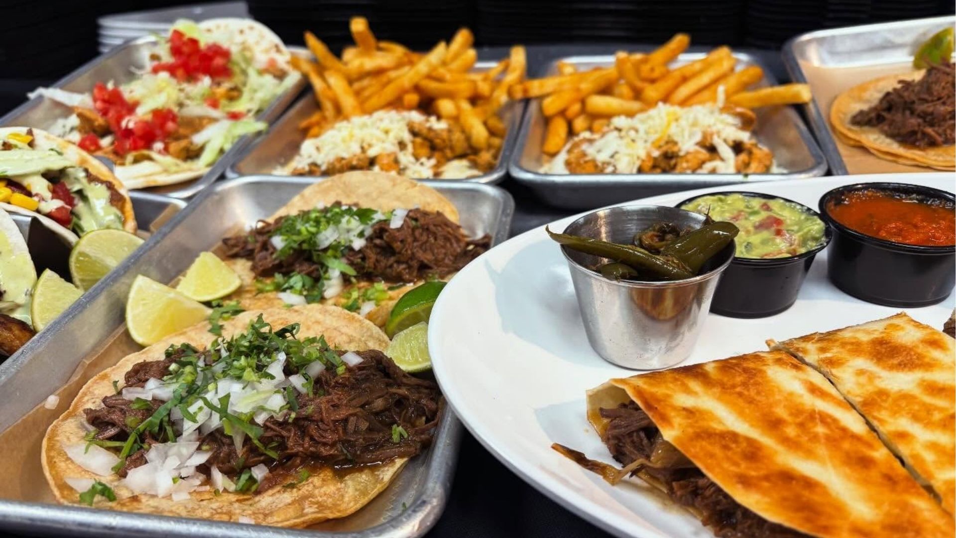 A vibrant platter of authentic Mexican street tacos from Atwater Street Tacos, showcasing various fillings and garnishes.